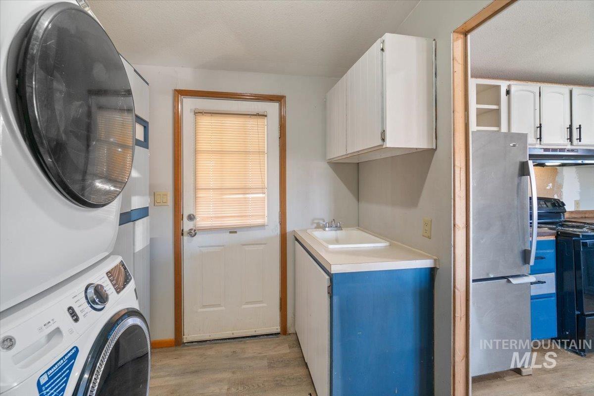 2284 Weiser River Road Weiser, ID 83672 - Photo 27 of 43 Laundry area with light wood-style flooring, stacked washing machine and dryer, and a textured ceiling