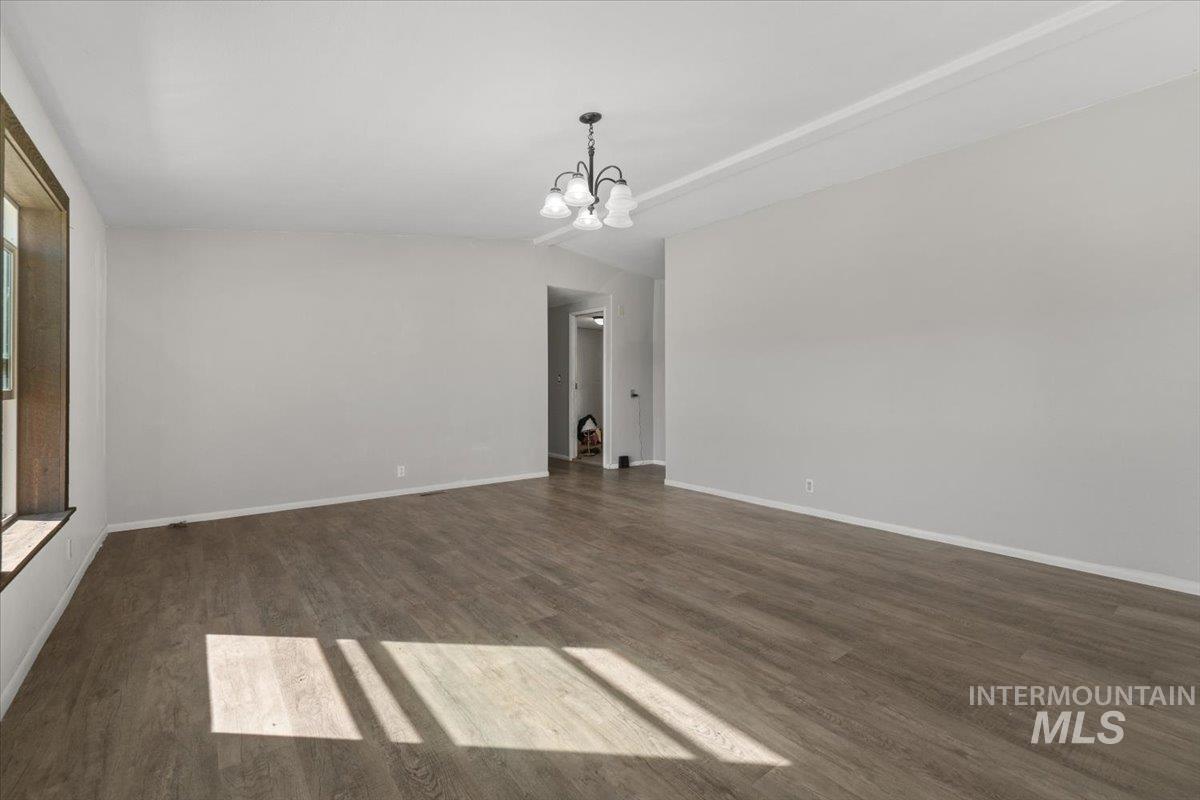 2284 Weiser River Road Weiser, ID 83672 - Photo 9 of 43 Unfurnished living room with dark wood-style floors, a chandelier, and vaulted ceiling