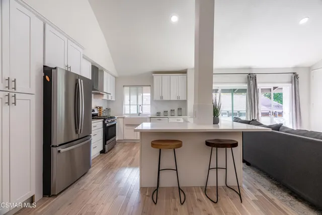 a kitchen with stainless steel appliances a dining table chairs refrigerator and sink