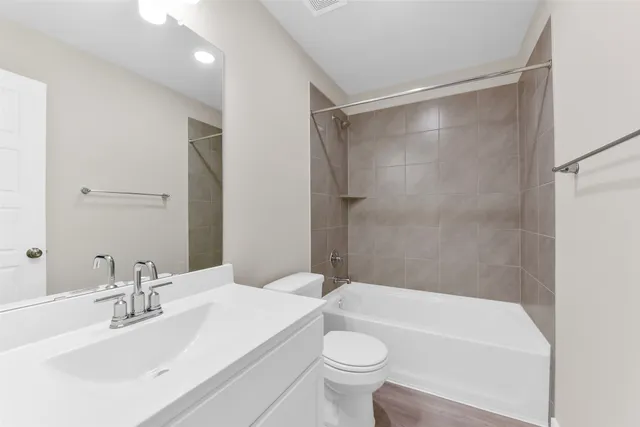 a bathroom with a bathtub shower sink vanity mirror and toilet