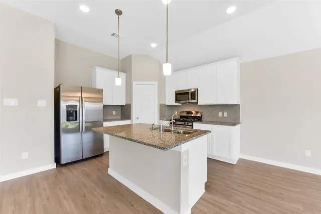 a kitchen with stainless steel appliances granite countertop a sink a stove and a refrigerator