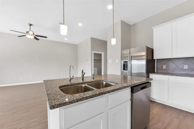 a kitchen with stainless steel appliances granite countertop a sink a refrigerator and a granite counter tops
