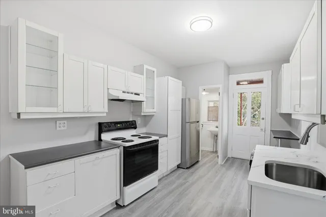 a kitchen with granite countertop a sink stove and refrigerator