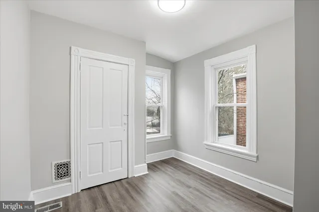 an empty room with wooden floor and windows