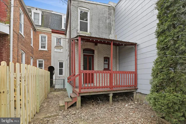 a view of a brick house with wooden fence and porch