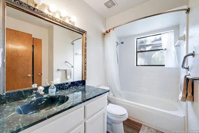 a bathroom with a granite countertop sink toilet and shower