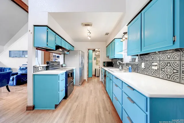 a large kitchen with stainless steel appliances granite countertop a lot of counter space and wooden floors