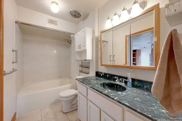 a bathroom with a granite countertop sink a toilet a mirror and bathtub