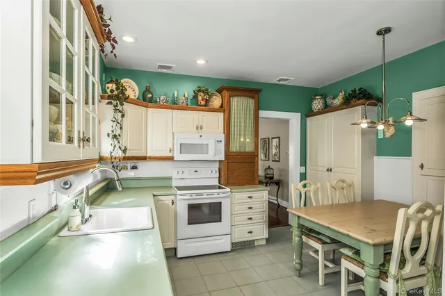 a large white kitchen with a stove a sink dishwasher and a refrigerator with wooden floor