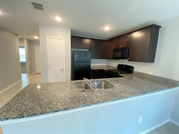 a kitchen with stainless steel appliances granite countertop a sink a refrigerator and a granite counter tops