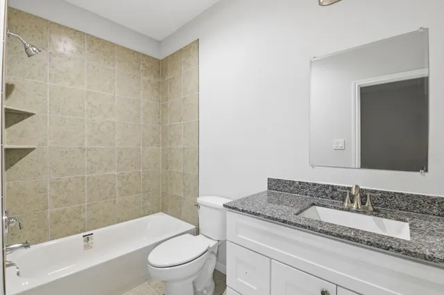 a bathroom with a granite countertop sink a toilet and shower