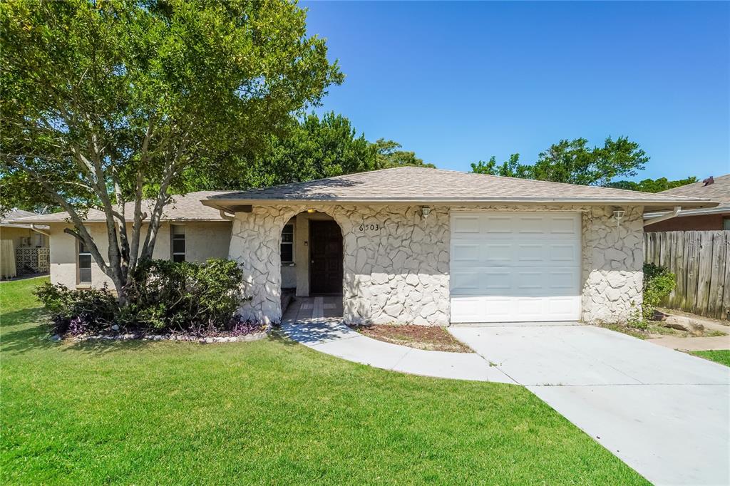 6503 Ridge Crest Drive Port Richey, FL 34668 - Photo 1 of 14 a front view of a house with a garden and yard