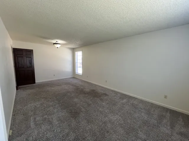 a view of an empty room with window and chandelier fan