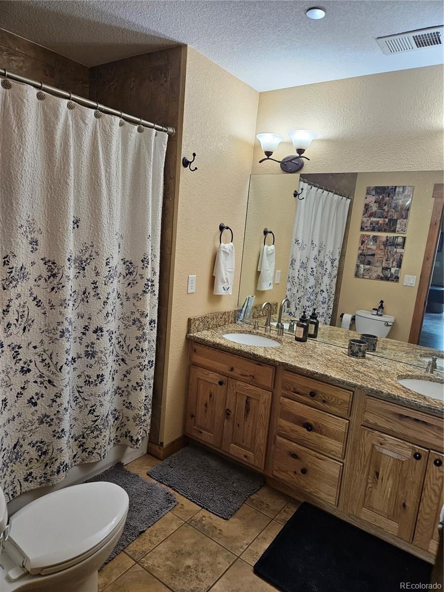 14514 Reserve Road Pine, CO 80470 - Photo 20 of 31 a bathroom with a granite countertop sink toilet a mirror a vanity and shower