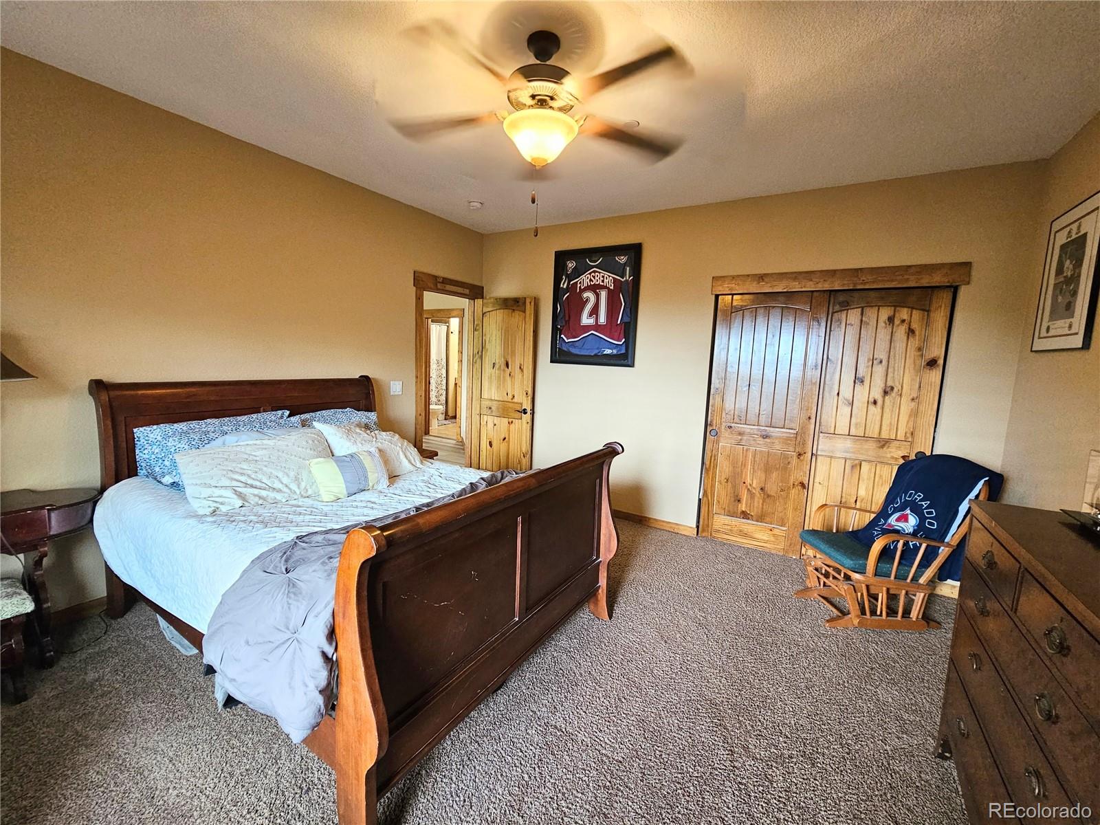 14514 Reserve Road Pine, CO 80470 - Photo 22 of 31 a bedroom with a bed and a chandelier