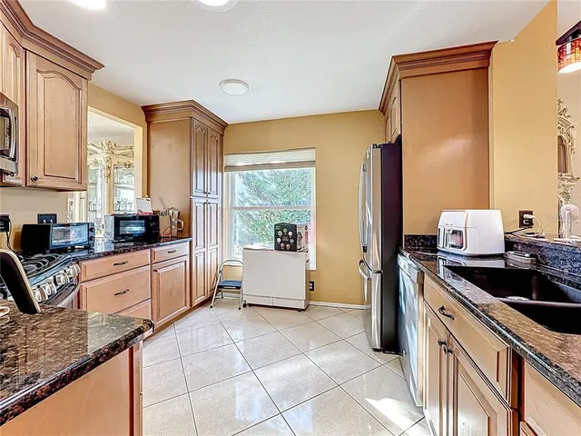 a kitchen with granite countertop a stove a sink and a refrigerator