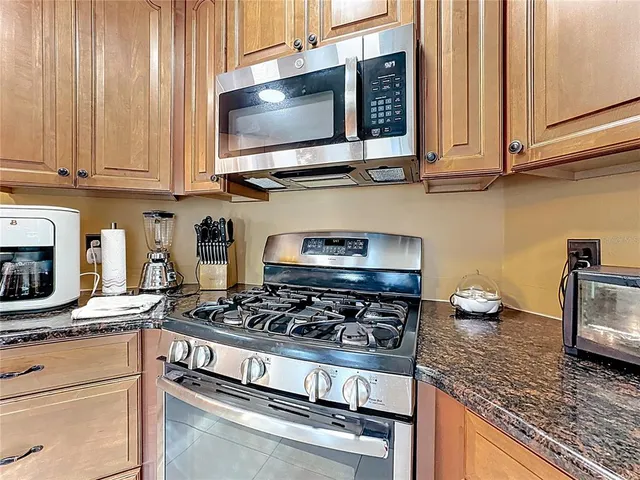 a kitchen with stainless steel appliances granite countertop a stove a sink and a microwave