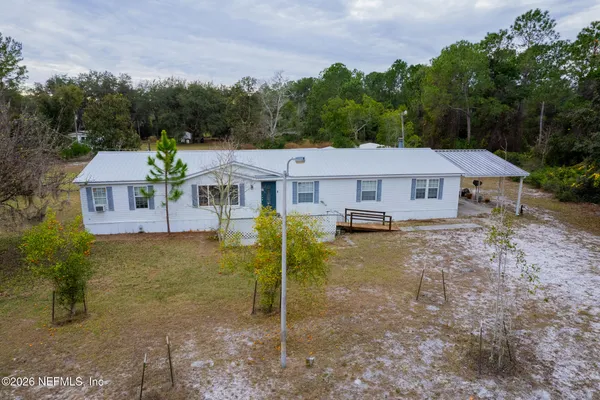 a aerial view of a house with swimming pool and trees in the background