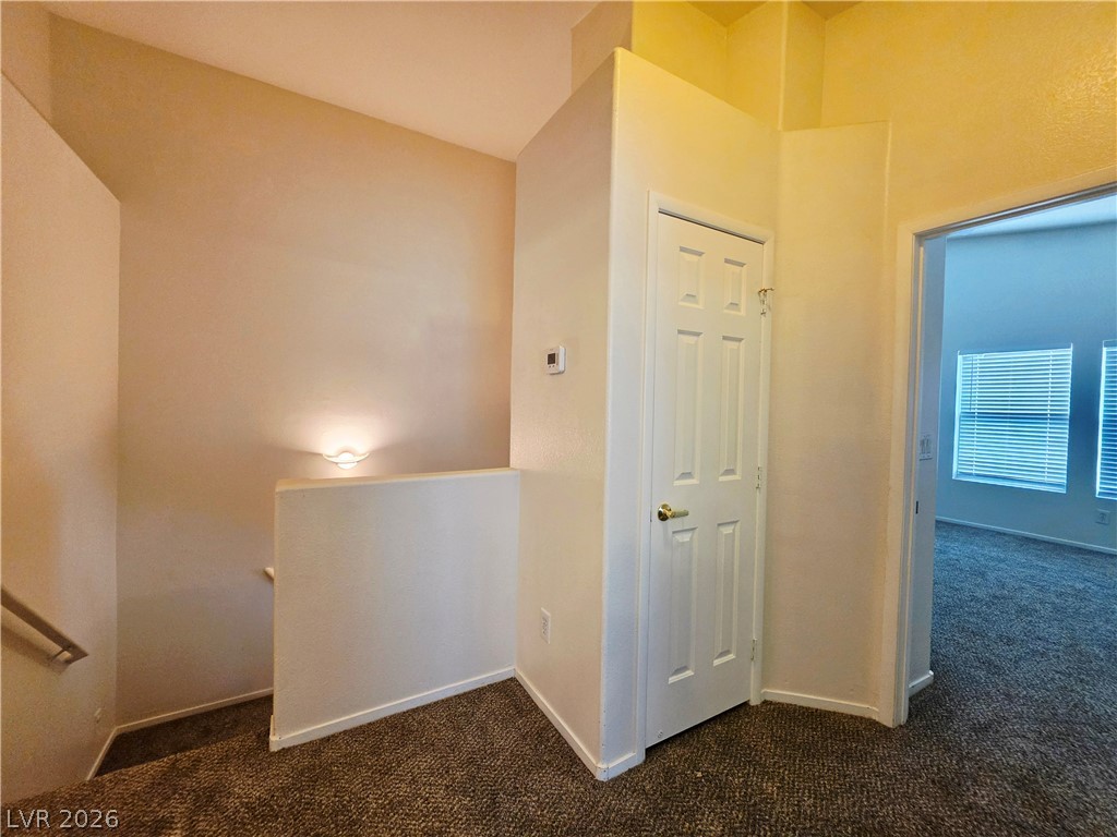 1571 Rusty Ridge Lane Henderson, NV 89002 - Photo 24 of 26 A well-lit landing area connects to a carpeted room beyond, featuring louvered window blinds.