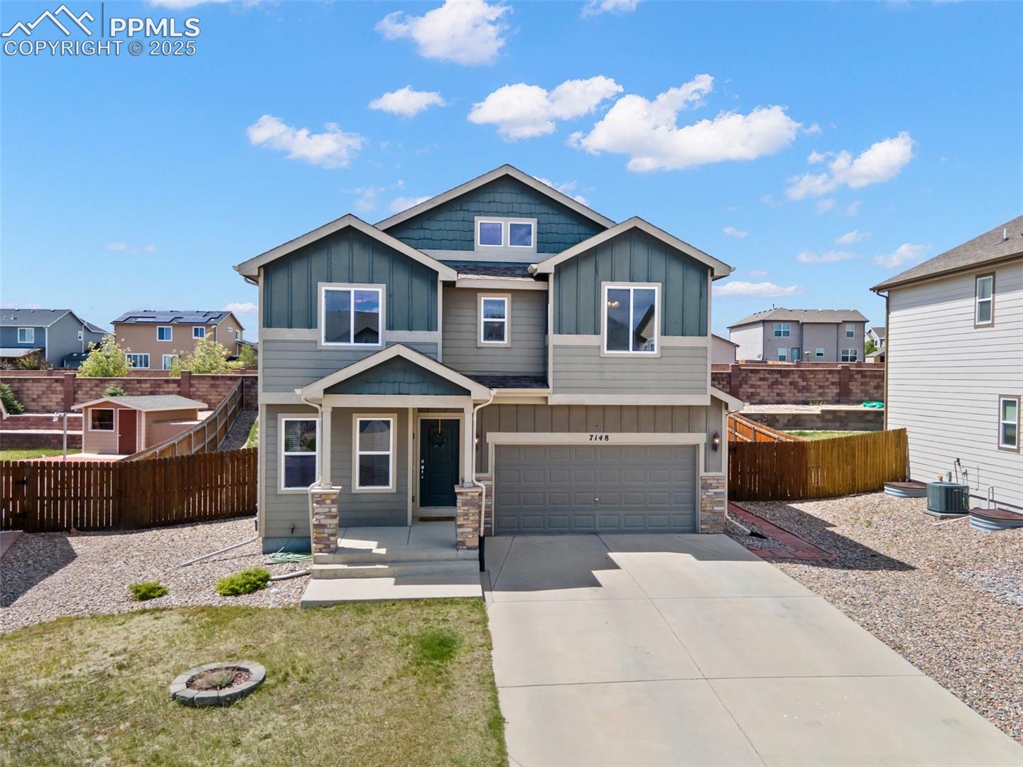 7148 Red Cardinal Loop Colorado Springs, CO 80908 - Photo 1 of 50 View of front of house with board and batten siding, stone siding, driveway, central AC, and an attached garage
