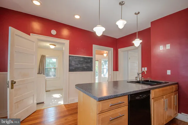 a kitchen with kitchen island granite countertop a sink cabinets and wooden floor
