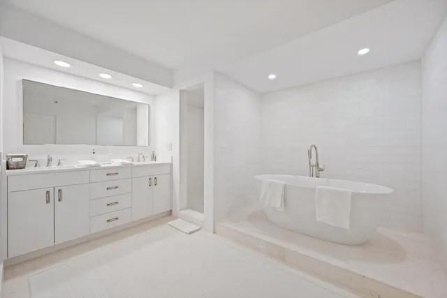 a spacious bathroom with a double vanity sink a mirror and a bathtub