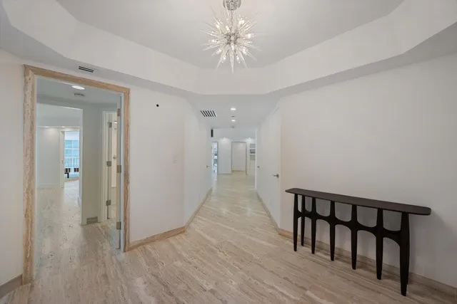 a view of a hallway with wooden floor and a chandelier fan