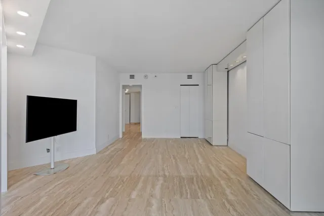 a view of an empty room with wooden floor and a flat screen tv