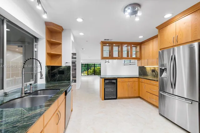 a kitchen with stainless steel appliances granite countertop a refrigerator a sink a stove and a wooden cabinets