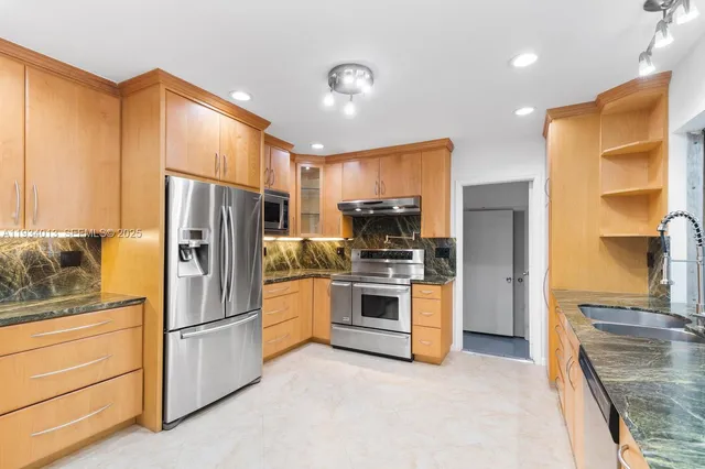 a kitchen with stainless steel appliances a refrigerator sink and stove
