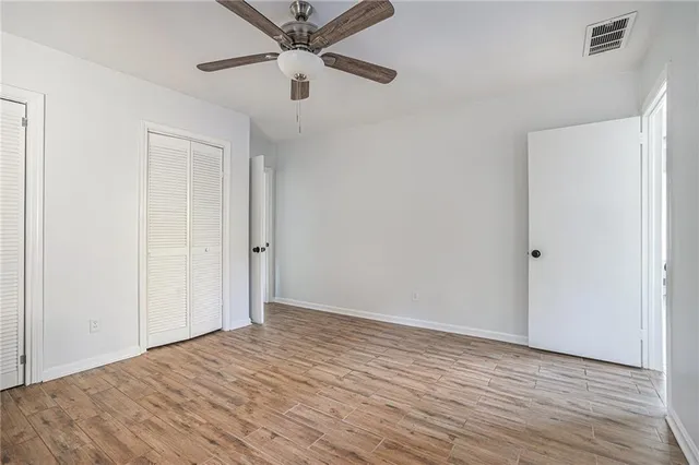 an empty room with wooden floor a ceiling fan and closet area