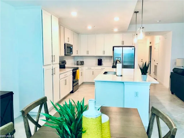 a kitchen with stainless steel appliances a sink a stove a refrigerator cabinets and a dining table