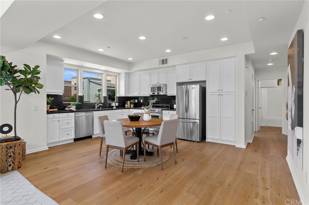 5429 Strand, Unit 101 Hawthorne, CA 90250 - Photo 6 of 39 a kitchen with stainless steel appliances kitchen island granite countertop a refrigerator a stove a sink a dining table and chairs with wooden floor