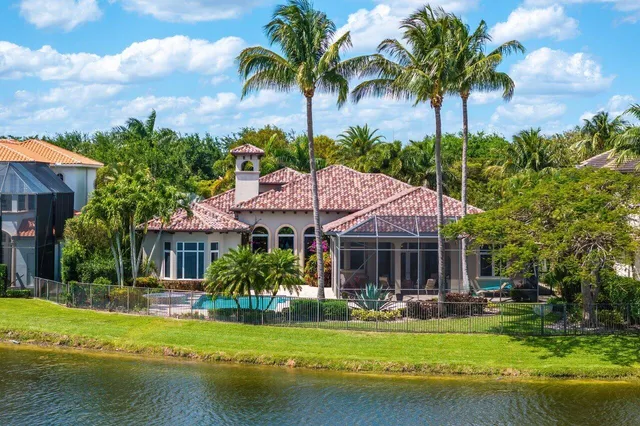 a palm tree sitting in front of a house with a garden