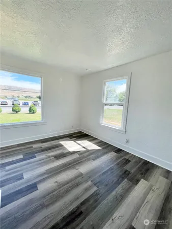 a view of empty room with window and wooden floor