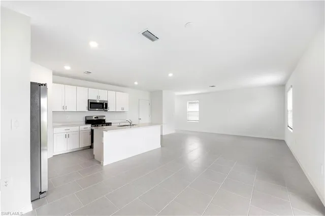 a large white kitchen with kitchen island a sink a stove a refrigerator and a refrigerator