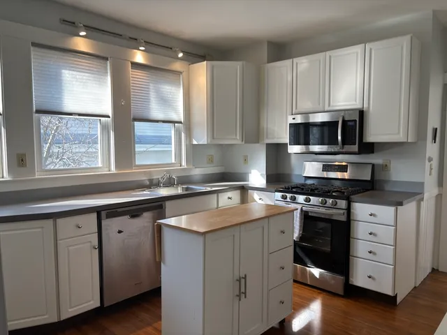 a kitchen with cabinets appliances a sink and a window