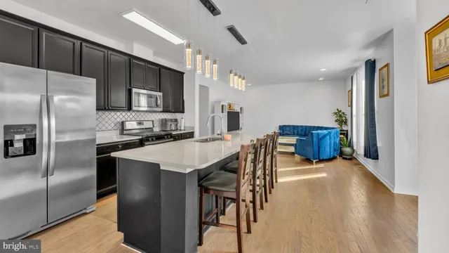a kitchen with stainless steel appliances kitchen island granite countertop a refrigerator a stove a microwave oven a sink with island and chairs