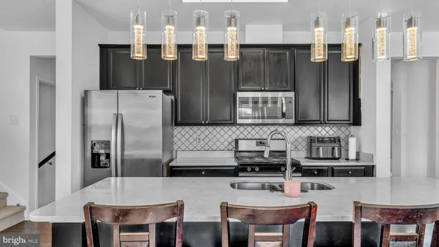 a kitchen with stainless steel appliances granite countertop a sink refrigerator and chairs