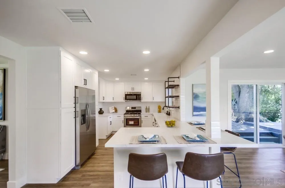 9841 Settle Road Santee, CA 92071 - Photo 21 of 46 a large kitchen with kitchen island a refrigerator a stove a dining table and chairs
