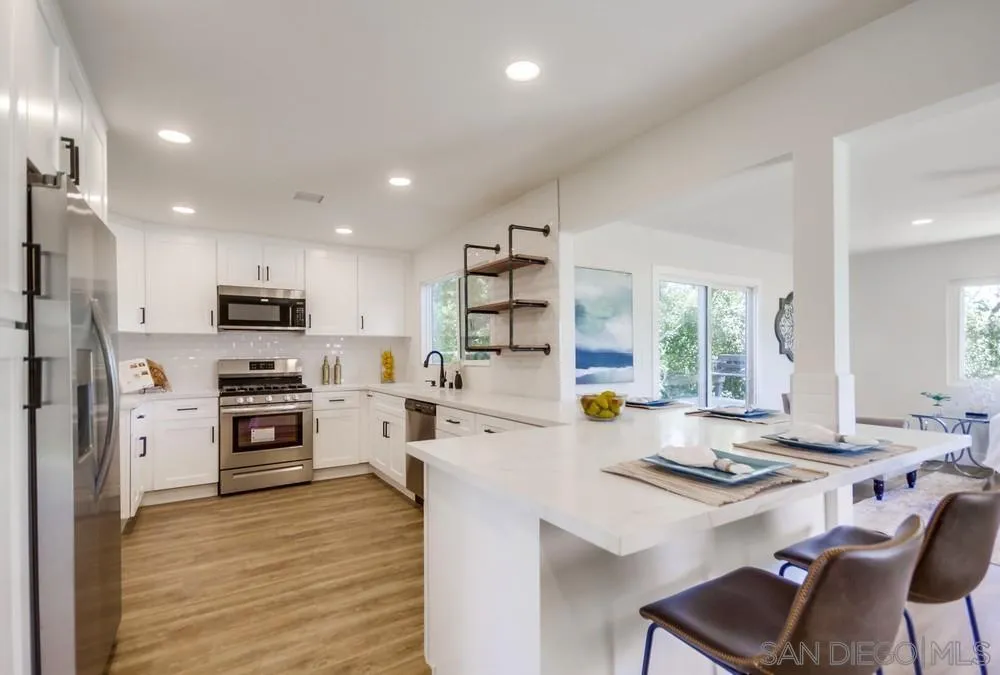 9841 Settle Road Santee, CA 92071 - Photo 22 of 46 a kitchen with a stove a sink dishwasher a refrigerator and a dining table with wooden floor