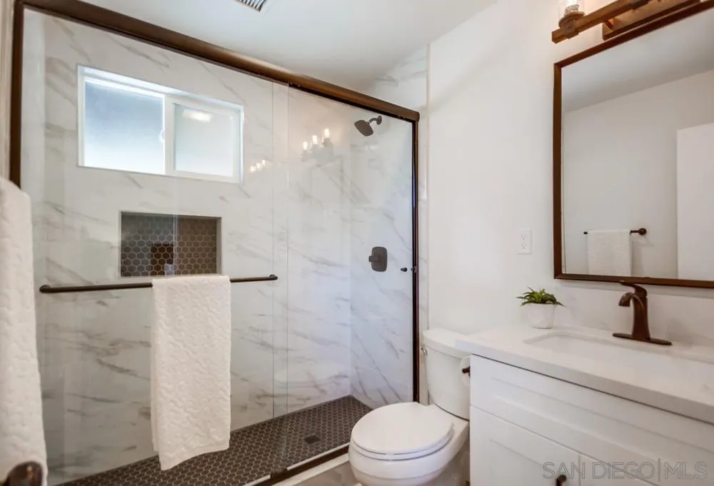 9841 Settle Road Santee, CA 92071 - Photo 30 of 46 a bathroom with a sink a toilet a mirror and shower