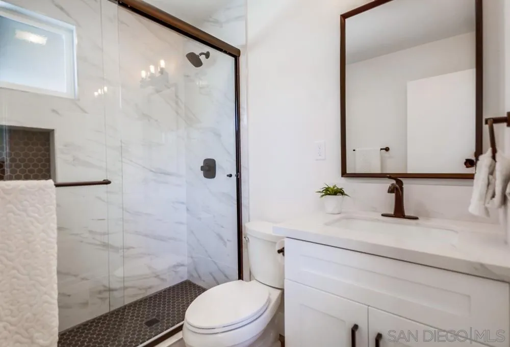 9841 Settle Road Santee, CA 92071 - Photo 32 of 46 a bathroom with a granite countertop sink toilet a mirror and shower