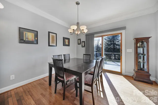 a dining room with wooden floor a chandelier a wooden table and chairs