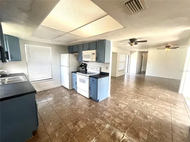a kitchen with granite countertop a stove a sink and a refrigerator