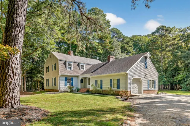 a front view of a house with a garden and trees