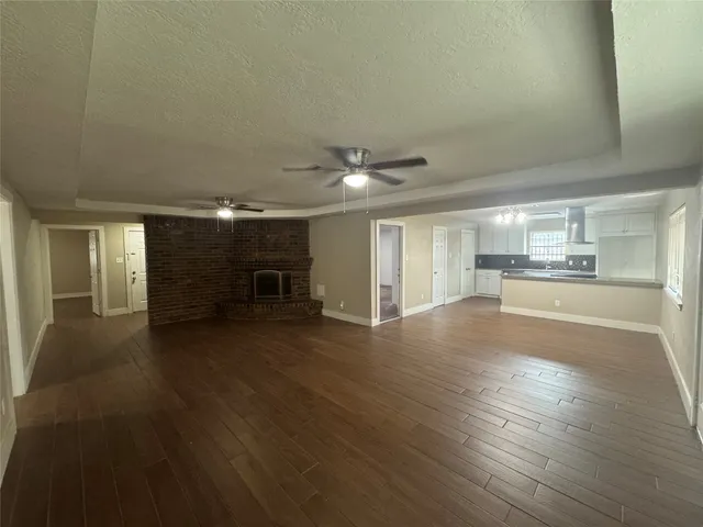 a view of a livingroom with wooden floor and a kitchen