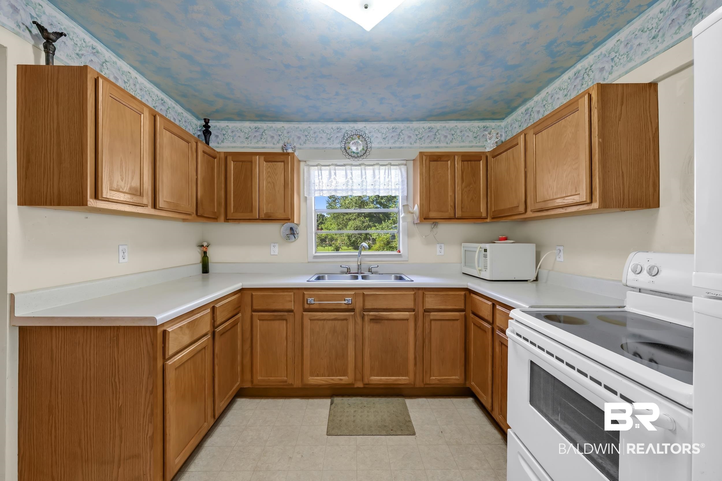 304 West Myrtle Avenue Foley, AL 36535 - Photo 7 of 29 U-shaped kitchen featuring wood cabinetry, light countertops, and a window above the sink