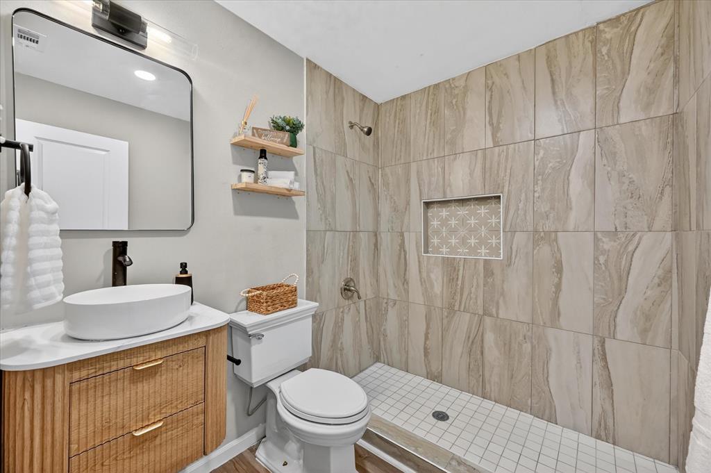 538 Pemberton Hill Road Dallas, TX 75217 - Photo 18 of 31 Contemporary bathroom featuring a wood-finish vanity with reeded details and brass hardware