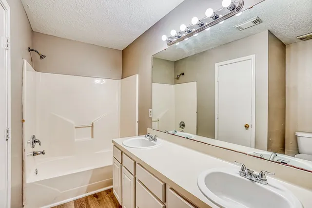a bathroom with a sink double vanity granite tub shower and a mirror